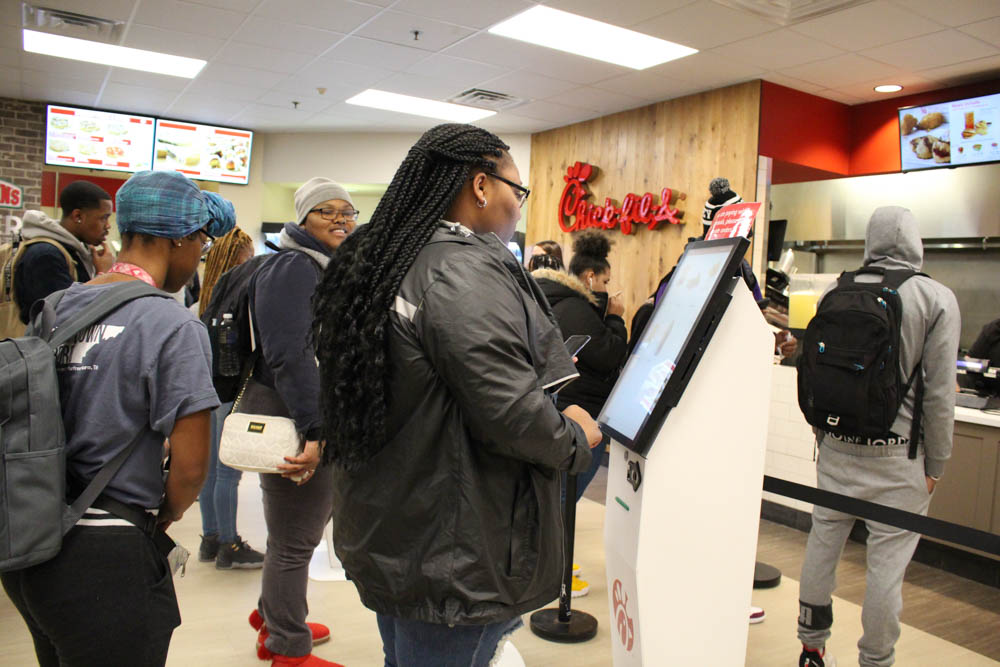 Students try the new, recently unveiled kiosks at Chick-fil-A to order themselves lunch (Photo by Joann Morales)