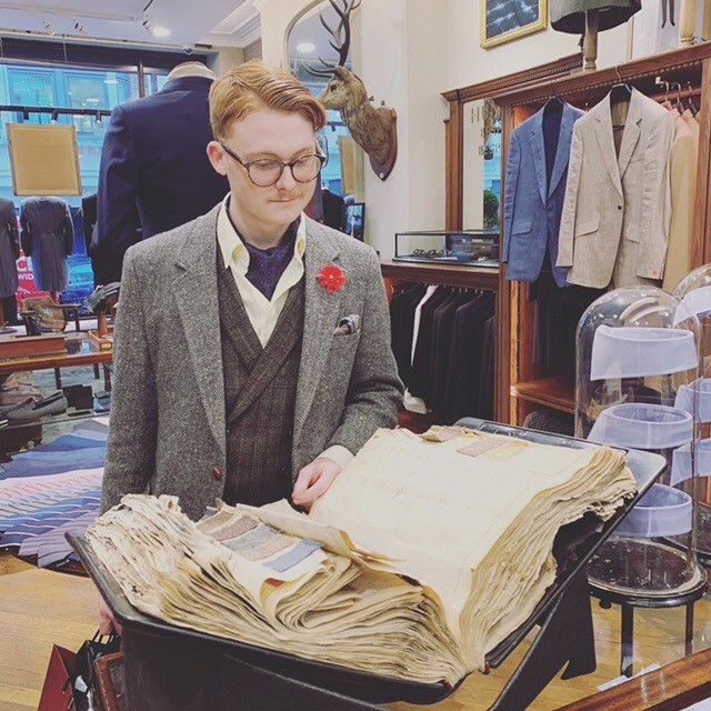 Tristan Sartor looking through a book of a collection of suit patterns made for royalty. SEAN SIPLE | THE ALL STATE