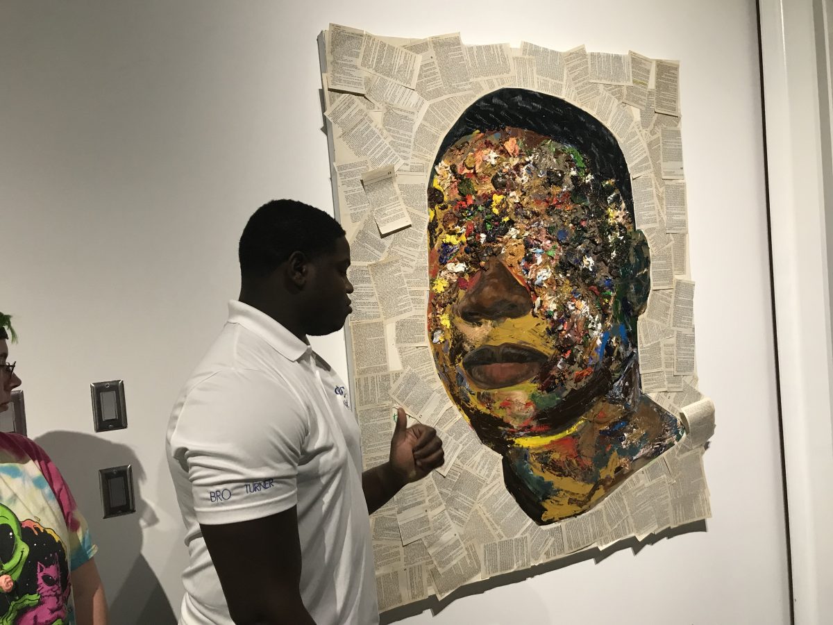 Khari Turner and his self-portrait titled “On any day I could be Tom” on Monday, April 15. This piece is on display in the Art and Design Building's Living Gallery until April 22. SEAN SIPLE | THE ALL STATE