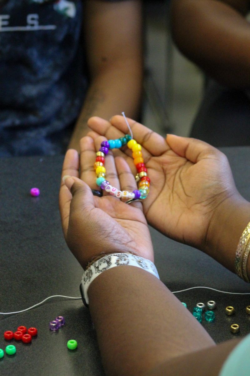 A student presents their newly made bracelet to a friend during SAGA’s DIY event.