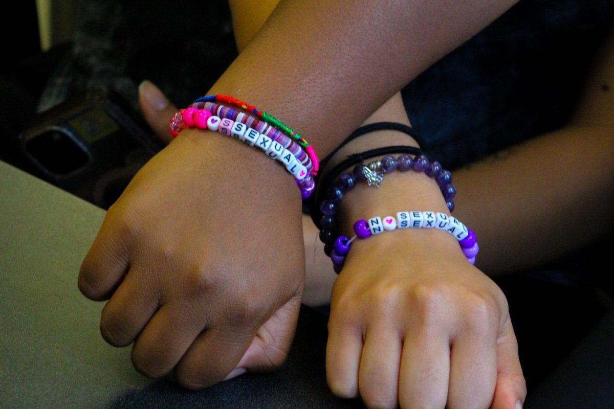 Students pose with matching bracelets in different colors, symbolizing inclusivity and Pride.