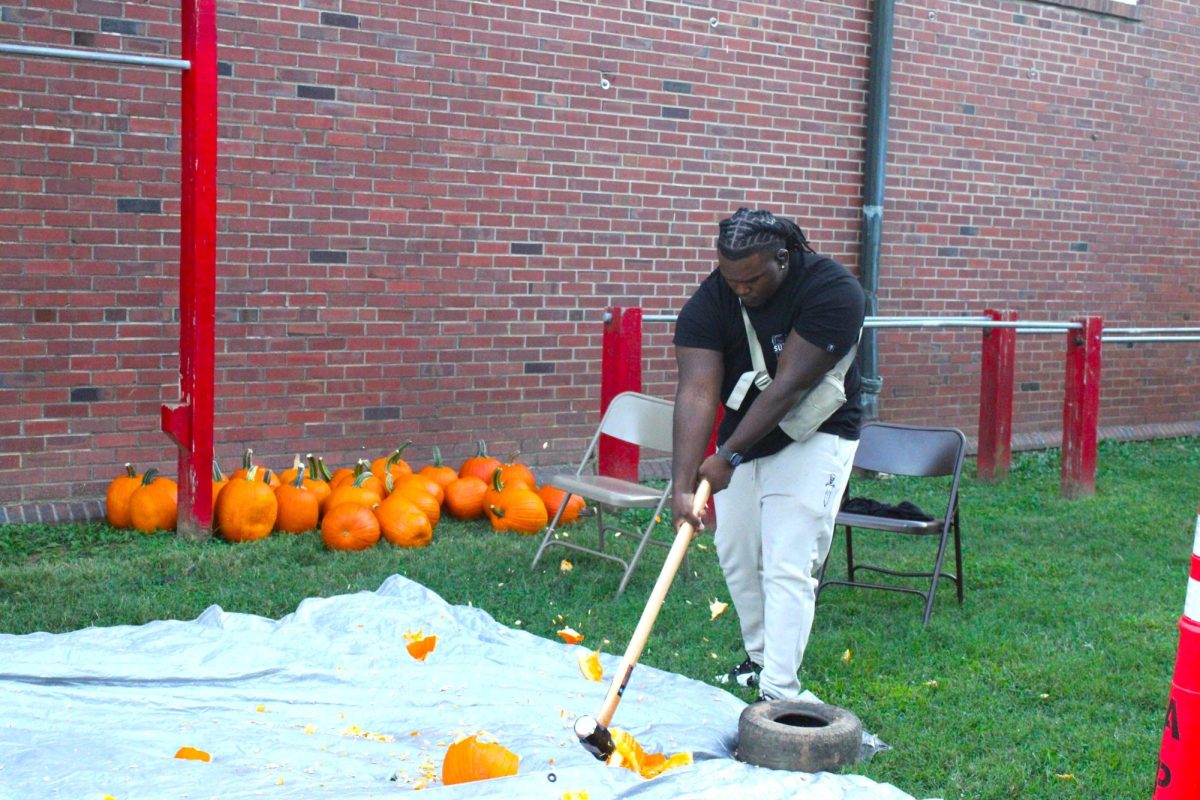 APSU students smashing a pumpkin outside the Red Barn at the Fall Festival.